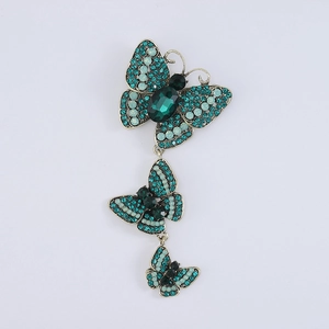 Detailed macro view of vintage bronze butterfly brooch with green crystal rhinestones
