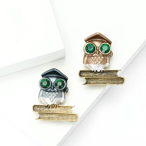 Fashionable minimalist owl brooches with green gemstone eyes in bronze and silver tones