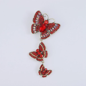 Detailed macro view of retro gold butterfly brooch featuring inlaid red crystals and gems
