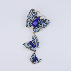 Detail of three blue crystal butterflies brooch in vintage gold finish with rhinestones