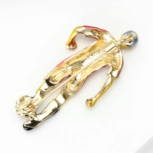 Back view of golden soccer player brooch with red accents and pin closure on white background