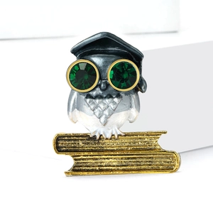 Chic owl brooch with graduation cap and green gemstone eyes on gold book base