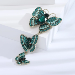 Vintage gold alloy triple butterfly brooch with green rhinestones on white display