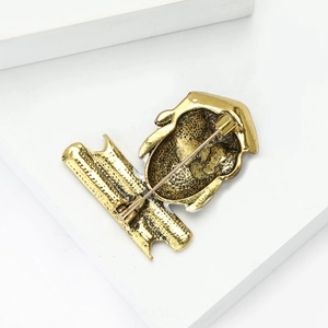 Macro shot of owl brooch back showing golden alloy texture and safety pin clasp mechanism