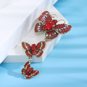 Vintage gold triple butterfly brooch with red crystals on a clean display stand