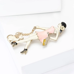 Détail d'une élégante broche en émail représentant une femme et un chat en rose et or