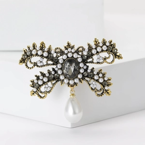 Vintage alloy bow brooch with white pearls and grey crystals on a gold base