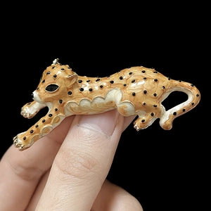 Detailed close-up of a running cheetah brooch in gold enamel with black leopard spots