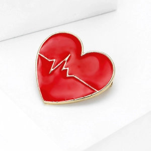 Spilla a cuore rossa minimalista con linee ECG dorate su supporto bianco