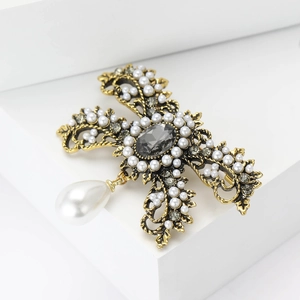 Vintage gold alloy brooch with white pearls and grey gems in a cross-radiant design