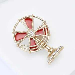 Detail of creative gold alloy electric fan brooch with red enamel and sparkling rhinestones