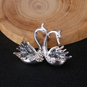 Détail de la broche double cygne argentée avec strass en cristal sur socle bois