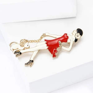 Détail d'une broche en émail montrant une femme en robe rouge avec un chat blanc