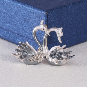 Détail de l'élégante broche double cygne avec strass sur cuir grainé blanc