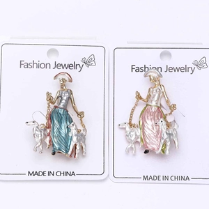 Detail view of two stylish alloy brooches featuring elegant ladies walking dogs in colorful enamel