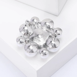 Vue détaillée du dos d'une broche fleur argentée avec épingle en métal et perles