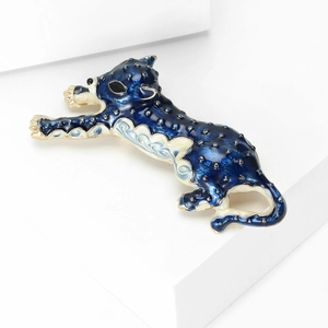 Macro shot of a blue and white enamel leopard brooch featuring detailed black spots