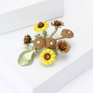 Broche de jarrón de girasol con piedras ámbar y cristales verdes sobre fondo blanco