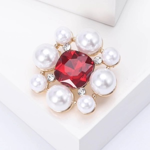 Gros plan détaillé d'une broche en forme de fleur avec gemme rouge et perles blanches