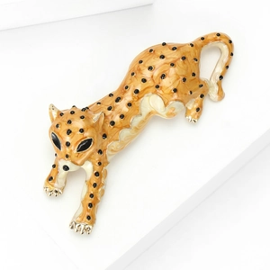 Detailed view of gold cheetah brooch featuring orange enamel and black leopard spots