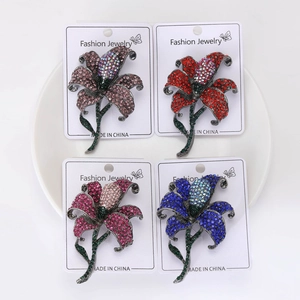 Detailed macro view of crystal lily brooches in four colors on white ceramic background