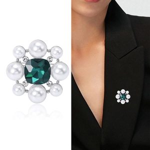 Broche vintage argentée avec pierre verte et perles sur un blazer noir élégant