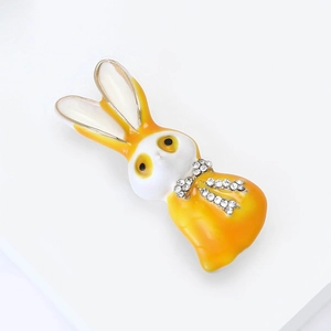 Makro-Detail der Emaille-Hasenbrosche mit glitzernder Strass-Schleife und vergoldeter Legierung