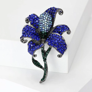 Close-up of lily brooch with blue crystals and gunmetal finish on a white block