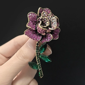 Detail of luxury rose brooch featuring purple rhinestones and vintage gold finish