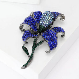 Sparkling lily flower brooch with blue rhinestones and green leaves on gunmetal alloy