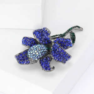 Detail of blue rose brooch with sparkling crystals on minimalist white surface