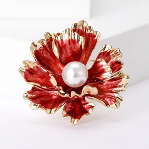 Macro shot of red enamel peony flower brooch with golden edges and a central white pearl