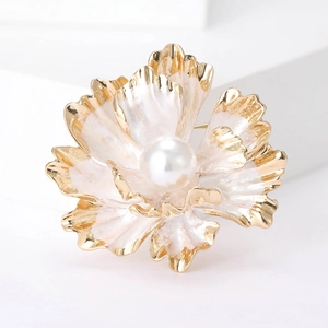 Detailed macro view of peony pearl brooch with gold edges on white marble block
