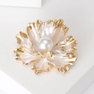 Macro shot of peony flower brooch with white enamel petals and a center pearl detail