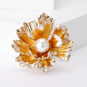 Macro view of a gold-toned floral brooch with a large central pearl on a stone block