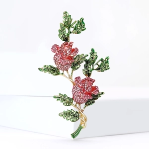 Élégante broche rose dorée avec strass roses et rouges sur un fond blanc minimaliste
