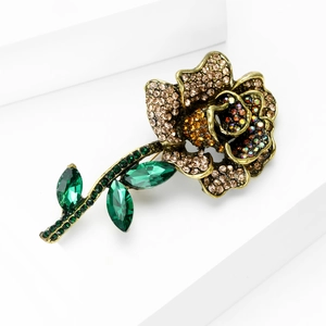 Close-up of vintage gold rose brooch with sparkling brown rhinestones and emerald crystals