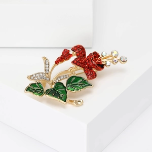 Elegant floral flower brooch with red rhinestones and green leaves on a gold base