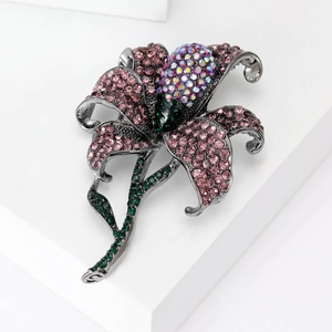 Exquisite pink crystal rose brooch with green leaf accents on a modern white display