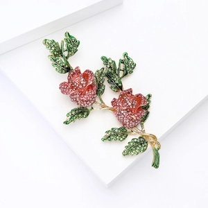 Détail de la broche rose avec cristaux roses et feuilles vertes sur plaqué or
