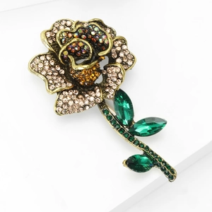Close-up of vintage rose brooch with pink rhinestones and emerald-cut green crystal leaves