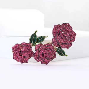 Vue détaillée de la broche rose avec strass roses et verts sur des supports blancs