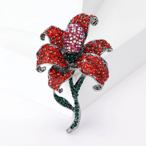Detailed close-up of rose brooch featuring red rhinestones and dark green crystal leaves
