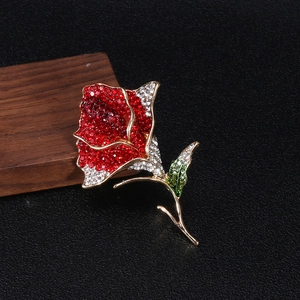 Macro detail of elegant rose brooch with red rhinestones and golden leaf accents