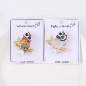 Detailed macro view of enamel owl brooches with faux pearls and crystals on card