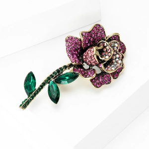 Detailed close-up of rose brooch with pink rhinestones and green emerald leaves