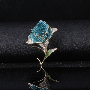 Detail of elegant rose flower brooch with blue crystals and gold-plated finish on black