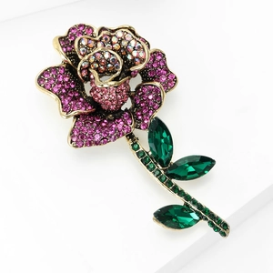 Detail of rose brooch featuring pink crystals and green gemstones in gold finish