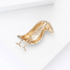 Detail view of the golden bird brooch back showing the safety pin clasp and metal finish