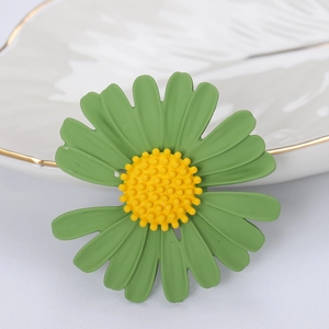 Dettaglio macro di spilla a margherita con petali verdi opachi su un piatto decorativo